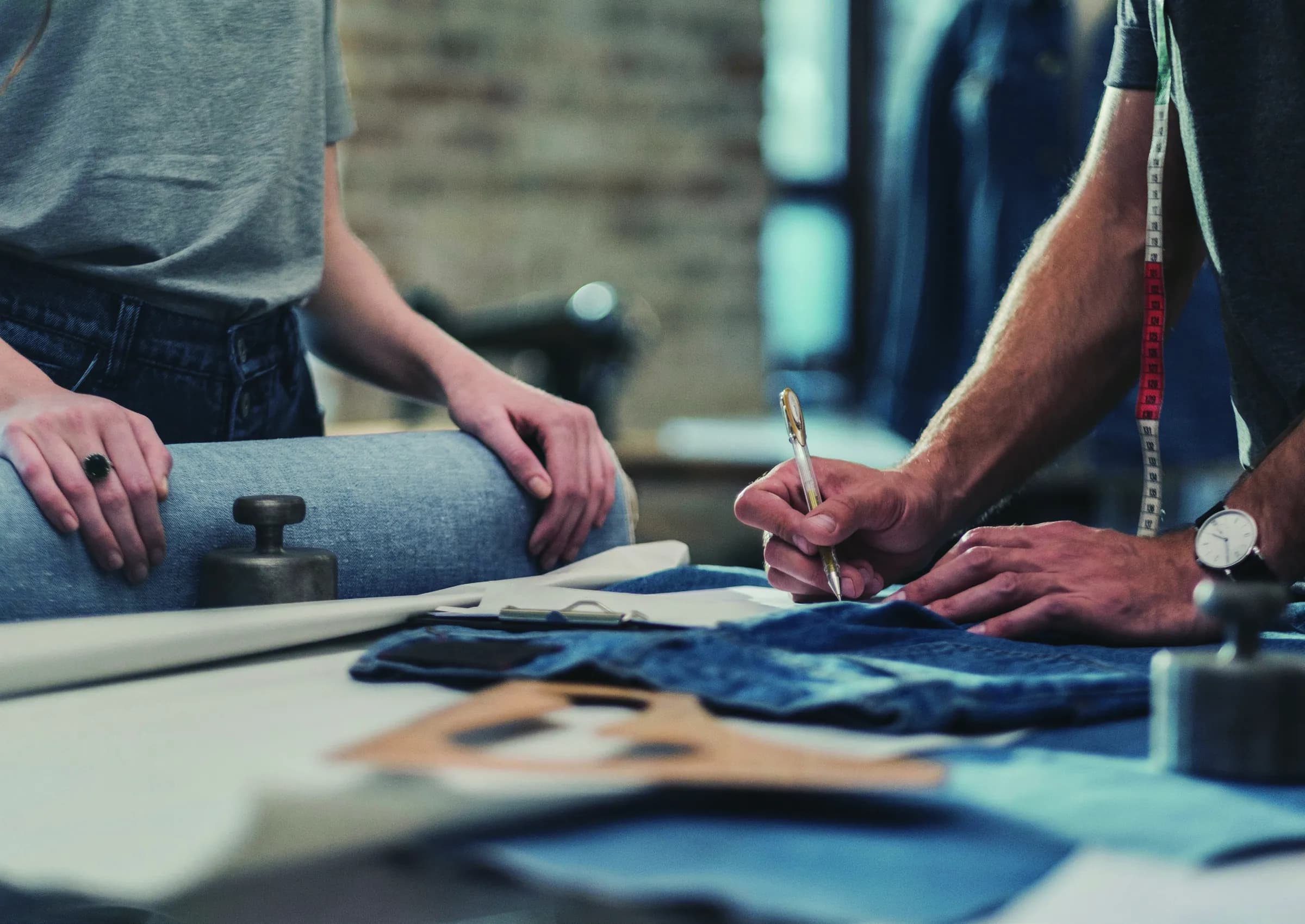 Two designers marking up a denim pattern on a studio table